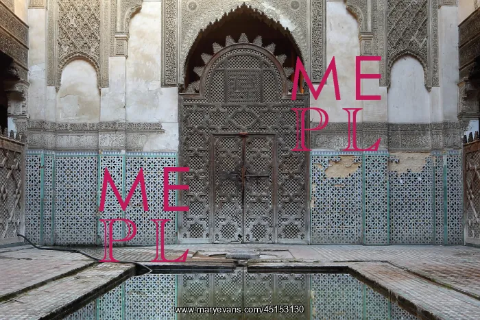 : Fez. Low angle view of main door to the central patio reflecting in pool in foreground : Fez. Low angle view of main door to the central patio reflecting in pool in foreground