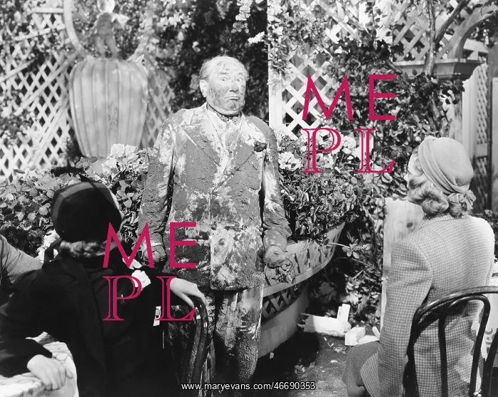 : Man covered in mud standing in front of two ladies : Man covered in mud standing in front of two ladies