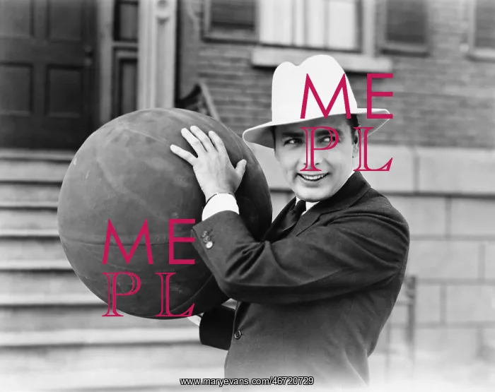: Man in hat holding large ball : Man in hat holding large ball