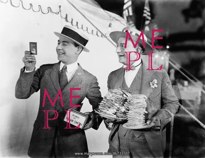 : Man holding plates of sandwiches with a man looking : Man holding plates of sandwiches with a man looking
