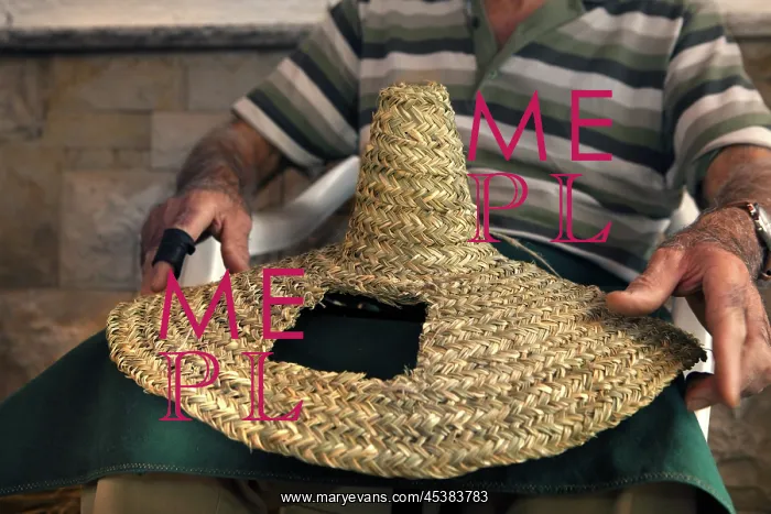 : Man holding a traditional woven hat made from : Man holding a traditional woven hat made from