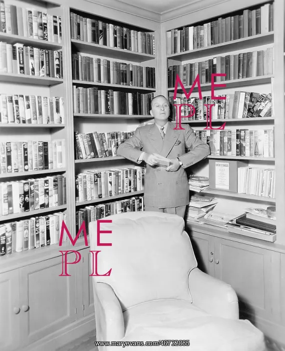 : Man leaning against a bookshelf in a library : Man leaning against a bookshelf in a library
