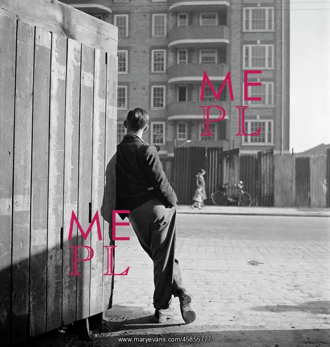 : A man leaning on a street corner hoarding : A man leaning on a street corner hoarding