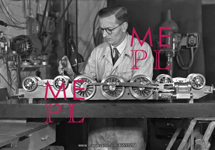 : Man in overalls working on miniature train : Man in overalls working on miniature train
