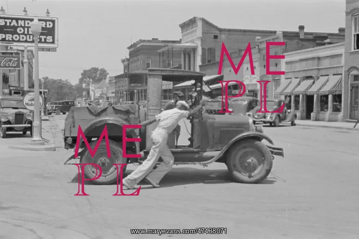 : Man pushing broken down car 1930s : Man pushing broken down car 1930s