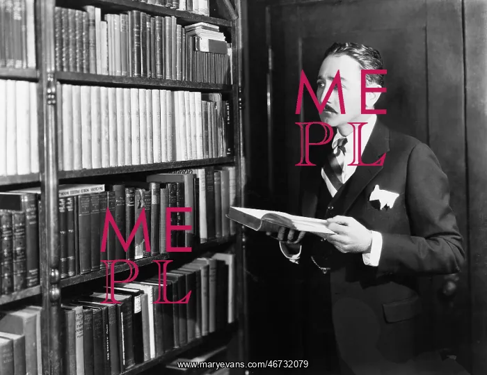 : Man selecting books from bookshelf in a library : Man selecting books from bookshelf in a library