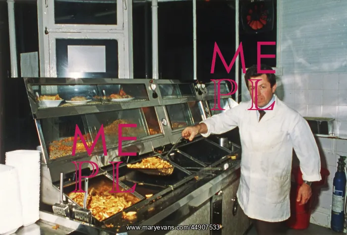 : Man serving in fish and chip shop, Cornwall : Man serving in fish and chip shop, Cornwall