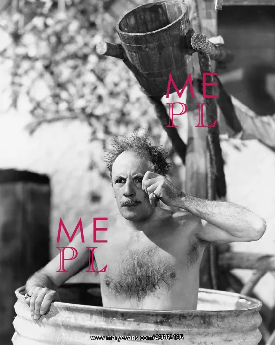 : Man sitting in a barrel taking a bath and looking : Man sitting in a barrel taking a bath and looking