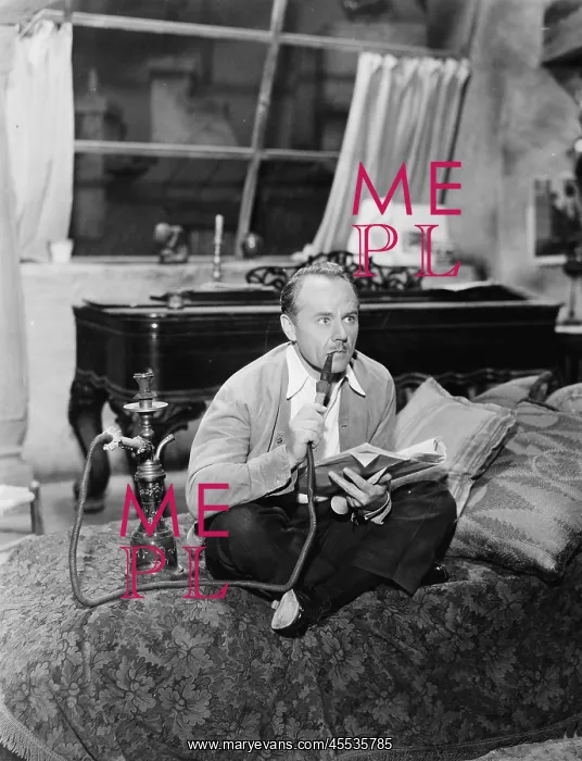 : Man sitting on a bed smoking his water pipe : Man sitting on a bed smoking his water pipe