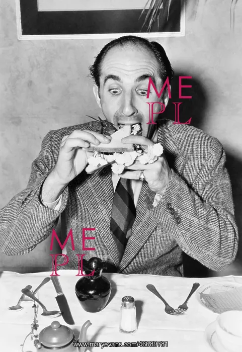 : Man sitting at a dining table and trying to eat a sandwich : Man sitting at a dining table and trying to eat a sandwich