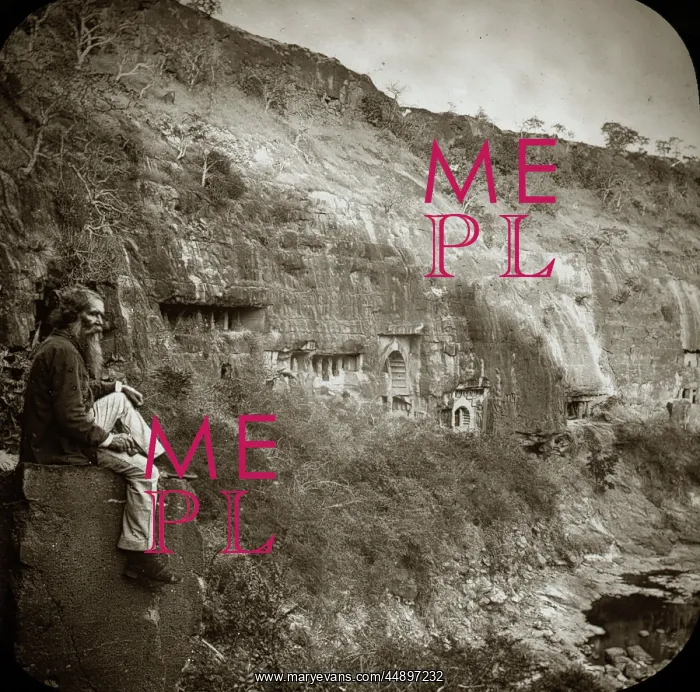 : A man sitting on a stone block next to a low cliff face : A man sitting on a stone block next to a low cliff face