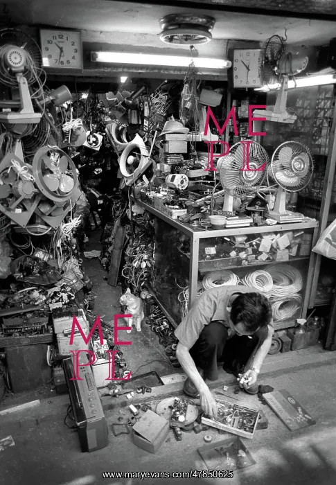 : Man squats on floor of his streetside workshop, Hong Kong : Man squats on floor of his streetside workshop, Hong Kong