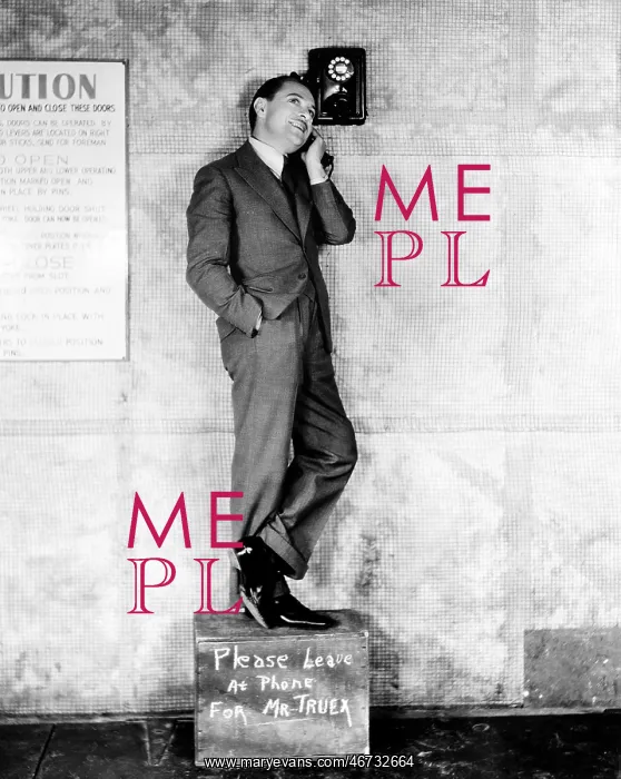 : Man standing on a box to reach the telephone : Man standing on a box to reach the telephone