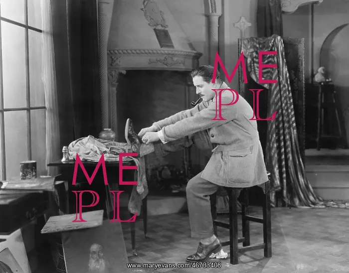 : Man in his studio putting on shoes : Man in his studio putting on shoes