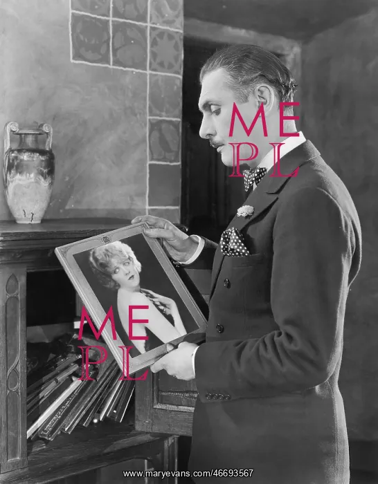 : Man studying a picture of a woman : Man studying a picture of a woman