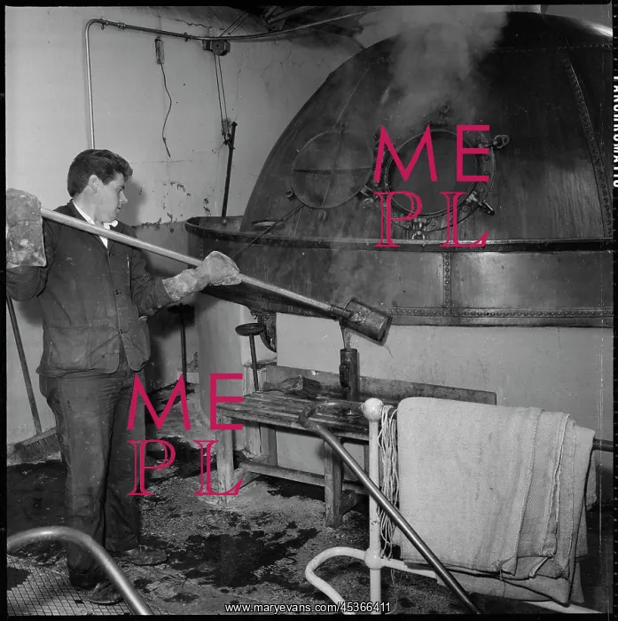 : A man taking a sample from a copper boiling kettle : A man taking a sample from a copper boiling kettle