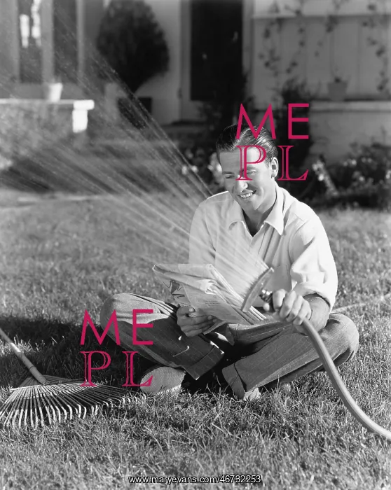  : Man watering the grass and reading