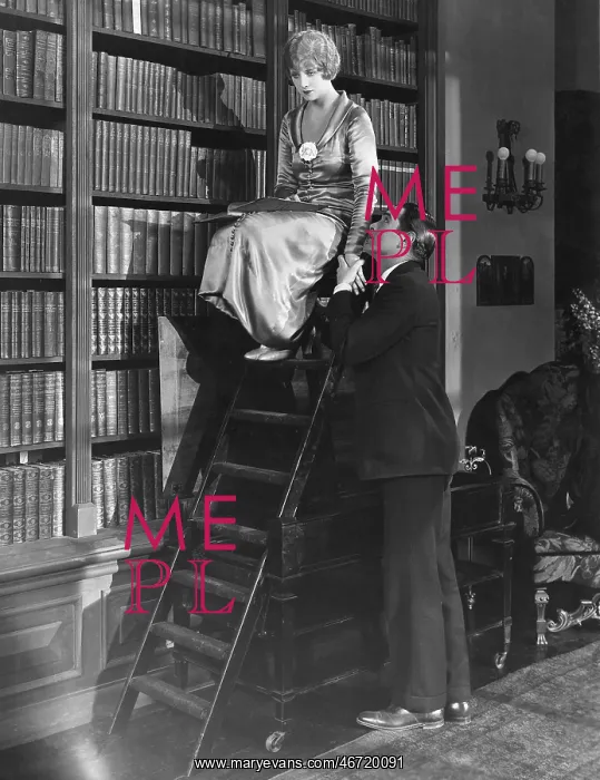 : Man with woman on ladder in library : Man with woman on ladder in library