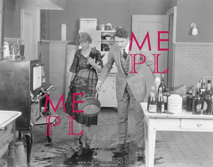: Man and woman looking at spilled liquid on kitchen floor : Man and woman looking at spilled liquid on kitchen floor