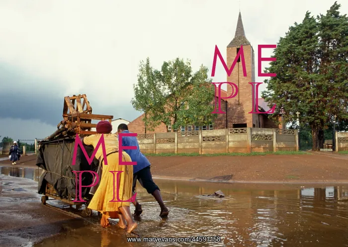 : Man and woman push a trolley, overloaded with : Man and woman push a trolley, overloaded with