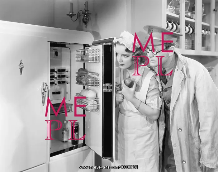 : Man and woman standing in front of a refrigerator : Man and woman standing in front of a refrigerator