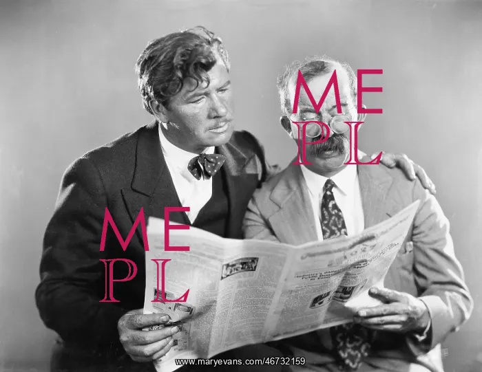 : Two mature men reading a newspaper together : Two mature men reading a newspaper together