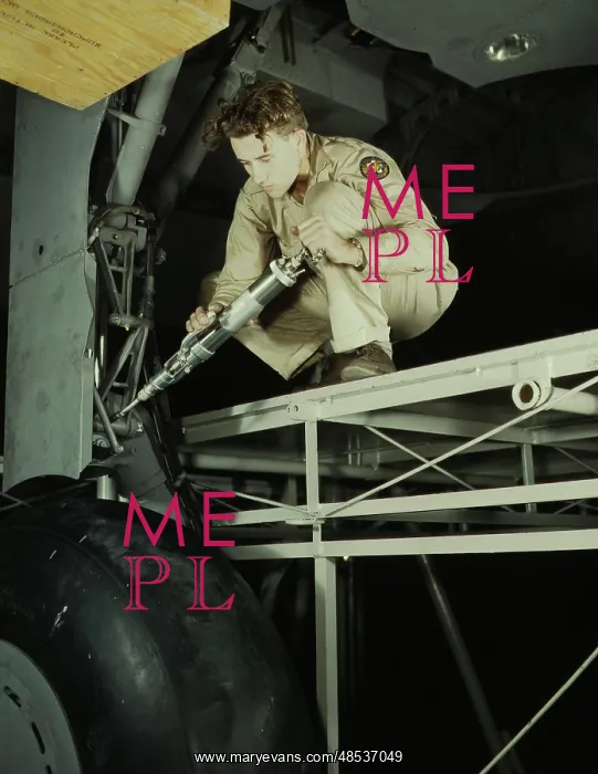 : A mechanic greasing the landing gear of a : A mechanic greasing the landing gear of a