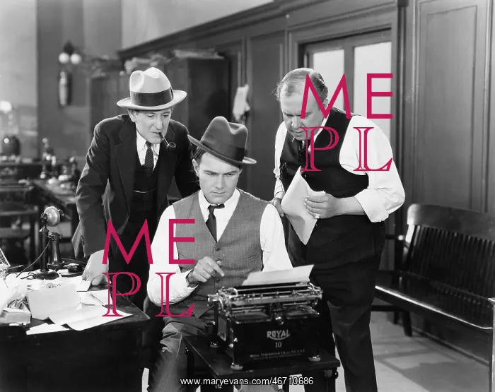 : Three men in an office hunched over a typewriter : Three men in an office hunched over a typewriter