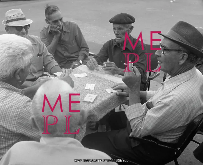 : Six men playing cards at a table in the street : Six men playing cards at a table in the street