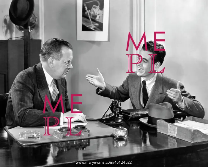 : Two Men Seated at Desk Younger Man Talking Gesturing : Two Men Seated at Desk Younger Man Talking Gesturing