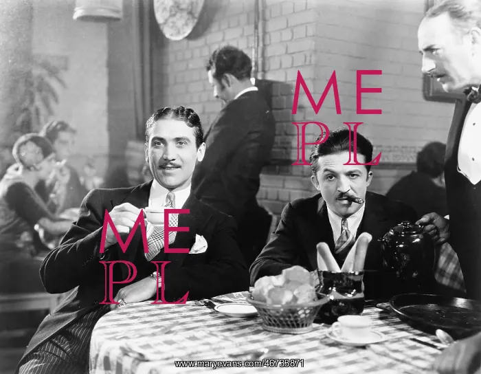 : Two men sitting together at a restaurant : Two men sitting together at a restaurant
