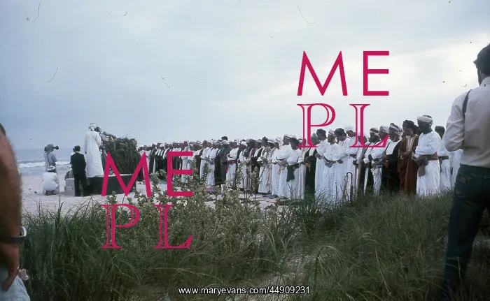 : Men stand praying by the beach in Oman : Men stand praying by the beach in Oman