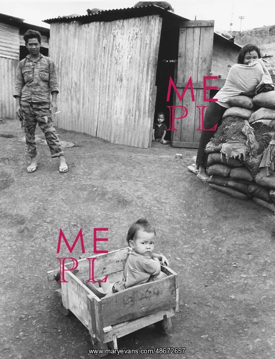 : A Montagnard child in a makeshift wagon is watched : A Montagnard child in a makeshift wagon is watched