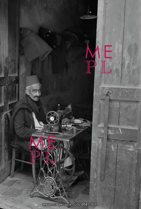 : A native craftsman at his sewing machine : A native craftsman at his sewing machine