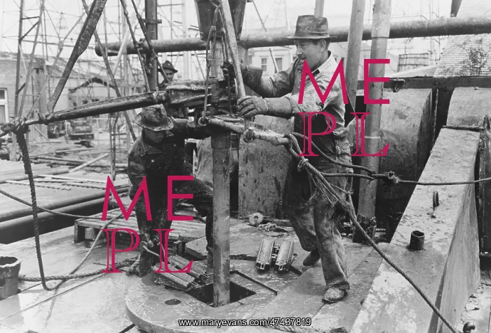 : Oil field workers adding a length of pipe to drill stream by : Oil field workers adding a length of pipe to drill stream by