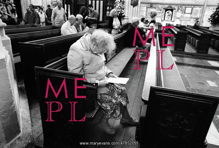 : An old lady sits in a pew in Bath Abbey : An old lady sits in a pew in Bath Abbey