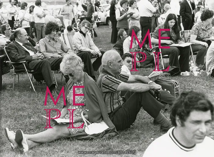 : Older couple sitting back-t-back at an outdoor show : Older couple sitting back-t-back at an outdoor show