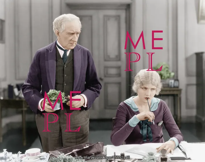 : Older man standing next to a woman at her desk : Older man standing next to a woman at her desk