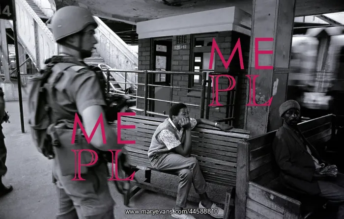 : Two people sit near a train station, watching : Two people sit near a train station, watching