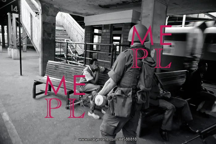 : Two people sit near a train station, watching : Two people sit near a train station, watching