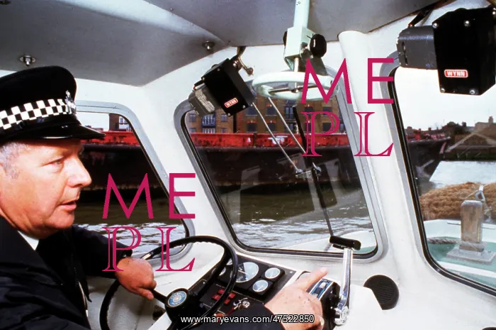 : Policeman at the controls of a riverboat : Policeman at the controls of a riverboat