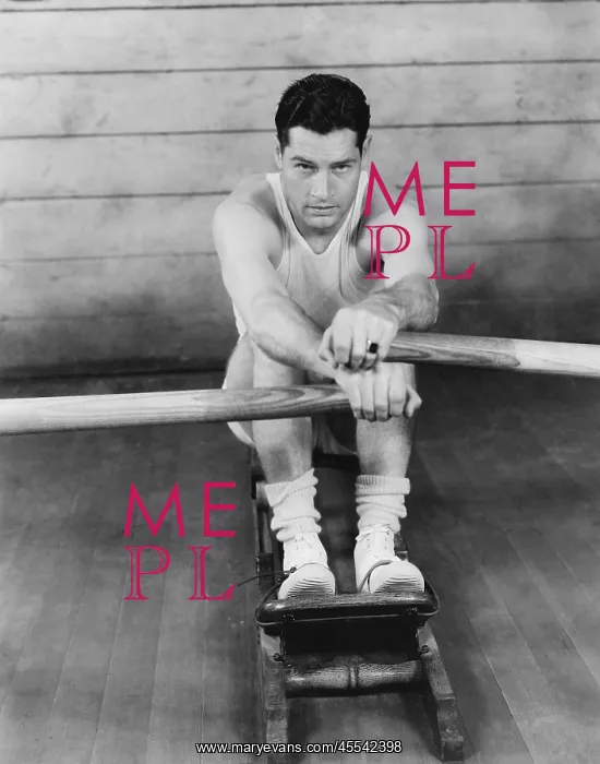 : Portrait of a young man exercising on a rowing machine : Portrait of a young man exercising on a rowing machine