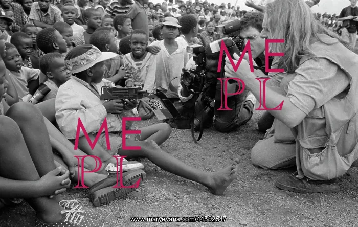 : Press photographers crowd around a child, holding : Press photographers crowd around a child, holding