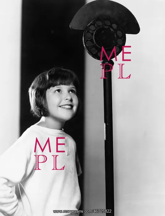 : Profile of a young girl looking at a microphone and smiling : Profile of a young girl looking at a microphone and smiling
