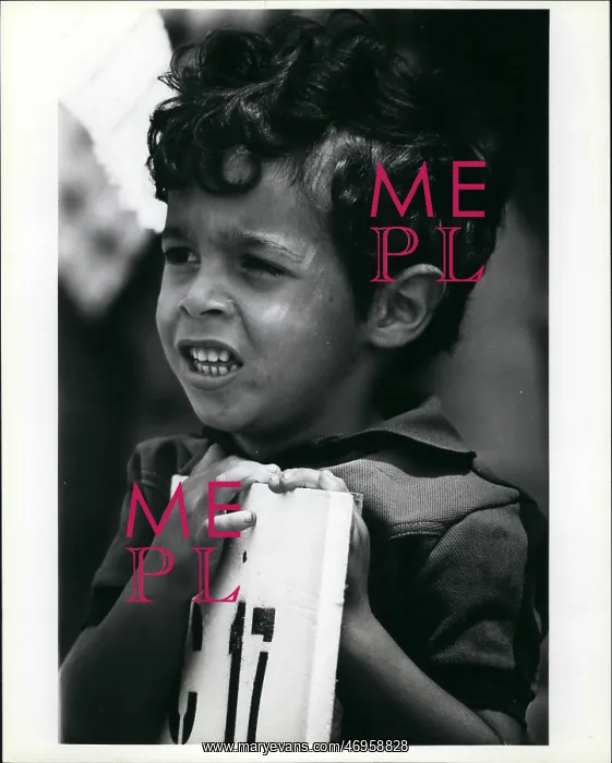 : Refugees. Mar. 22 A young Cuban refugee leans against the sign that shows : Refugees. Mar. 22 A young Cuban refugee leans against the sign that shows