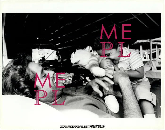 : Refugees. A Cuban refugee plays with his son as they lay on the cot assigned : Refugees. A Cuban refugee plays with his son as they lay on the cot assigned