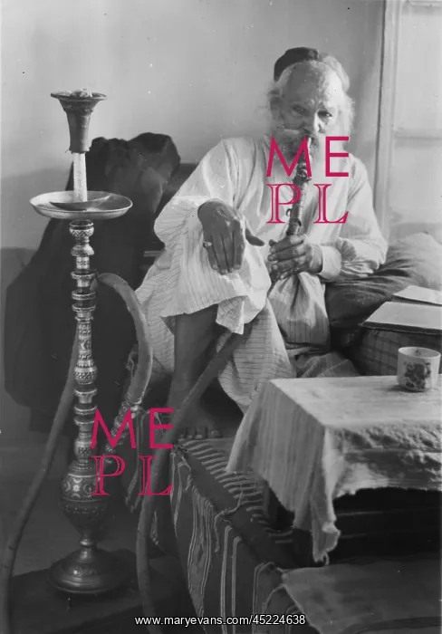 : Seated man smoking a nargile, or water pipe, ? : Seated man smoking a nargile, or water pipe, ?