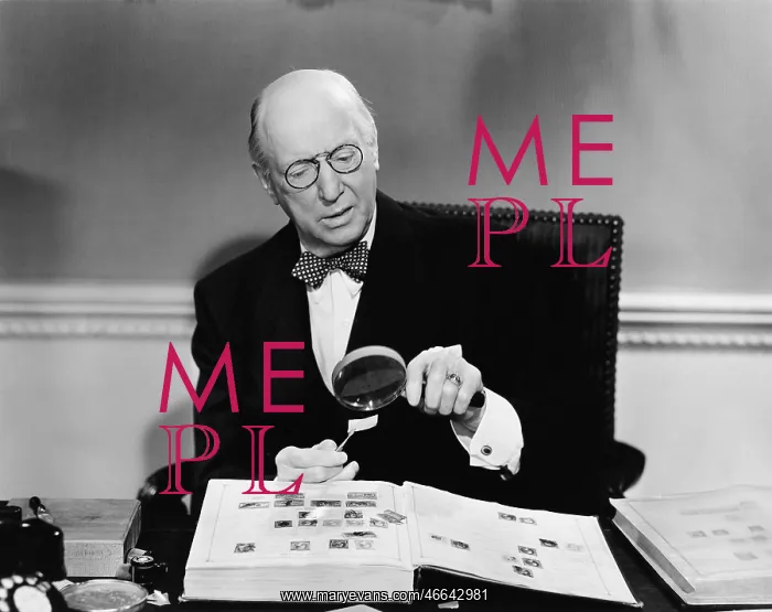 : Senior man examining a postage stamp with a magnifying : Senior man examining a postage stamp with a magnifying