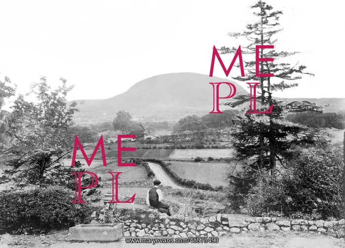 : Slemish - a view of Slemish with a man in the foreground sitting beside a water pump : Slemish - a view of Slemish with a man in the foreground sitting beside a water pump