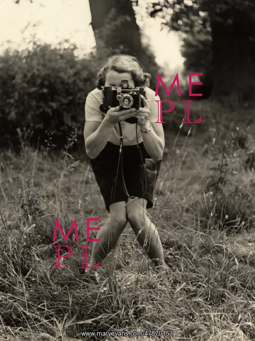  : Smile!. A woman with a camera adopts a photographer's pose for - another photographer